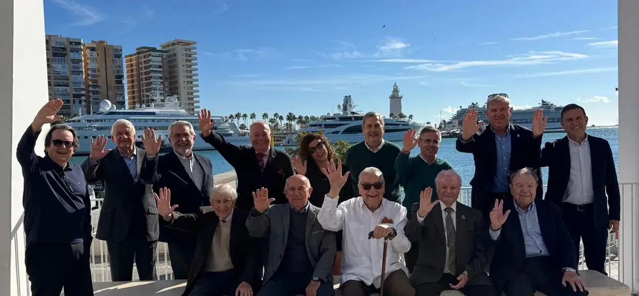 Grupo de profesionales saludándose en puerto con yates de fondo.